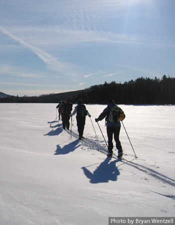 Cross-country skiers skiing across a Maine lake.